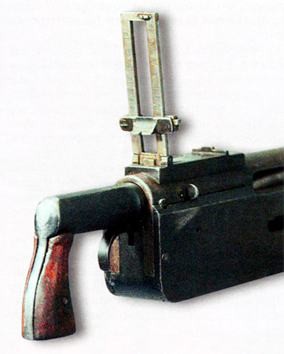 Затыльник пулемета «Кольт» с рукояткой и спусковым крючком. С правой стороны ствольной коробки виден замыкатель затыльника. Рамка прицела поднята